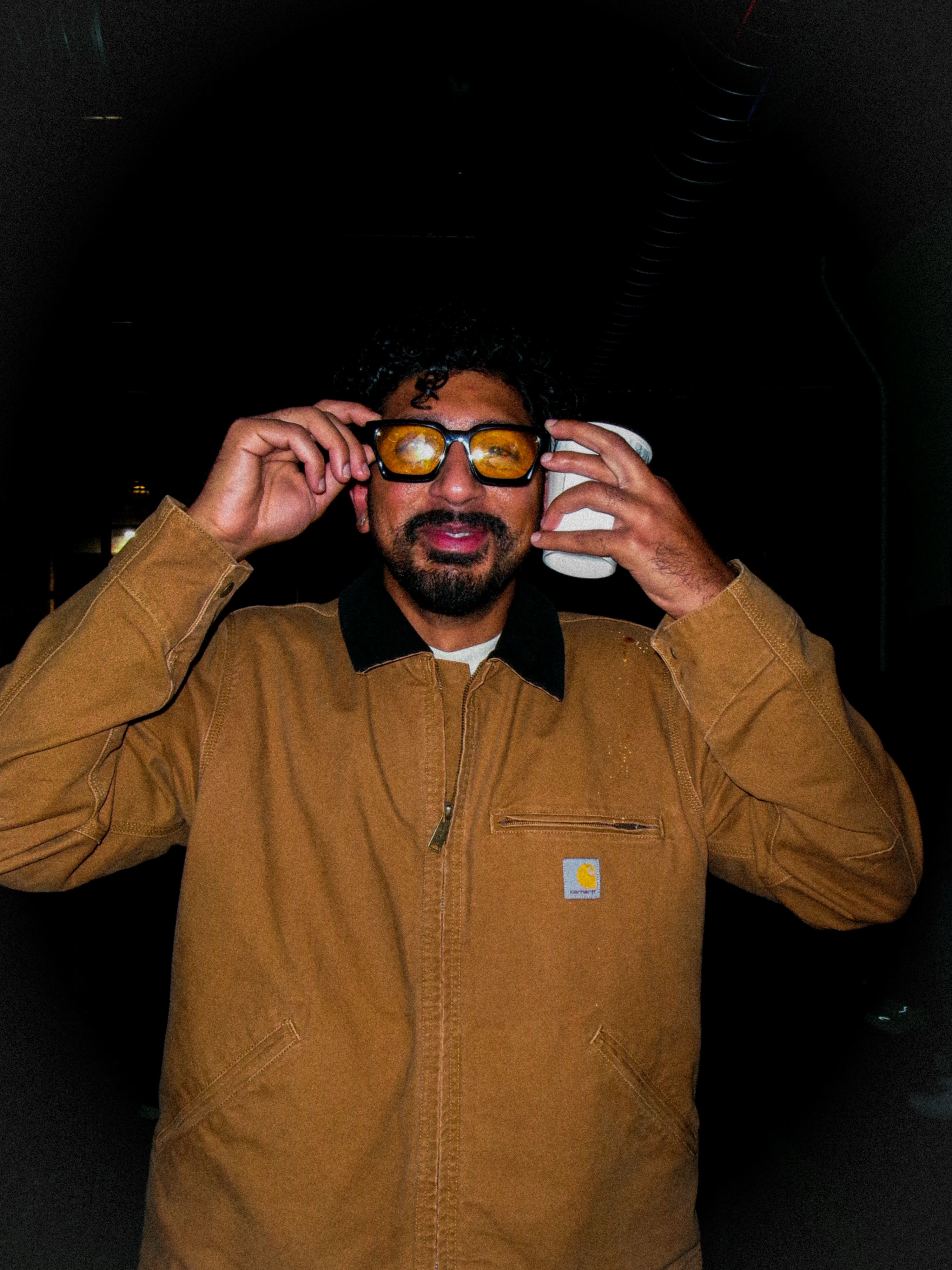 Vishnu Akella in a Carhartt jacket, adjusting amber sunglasses